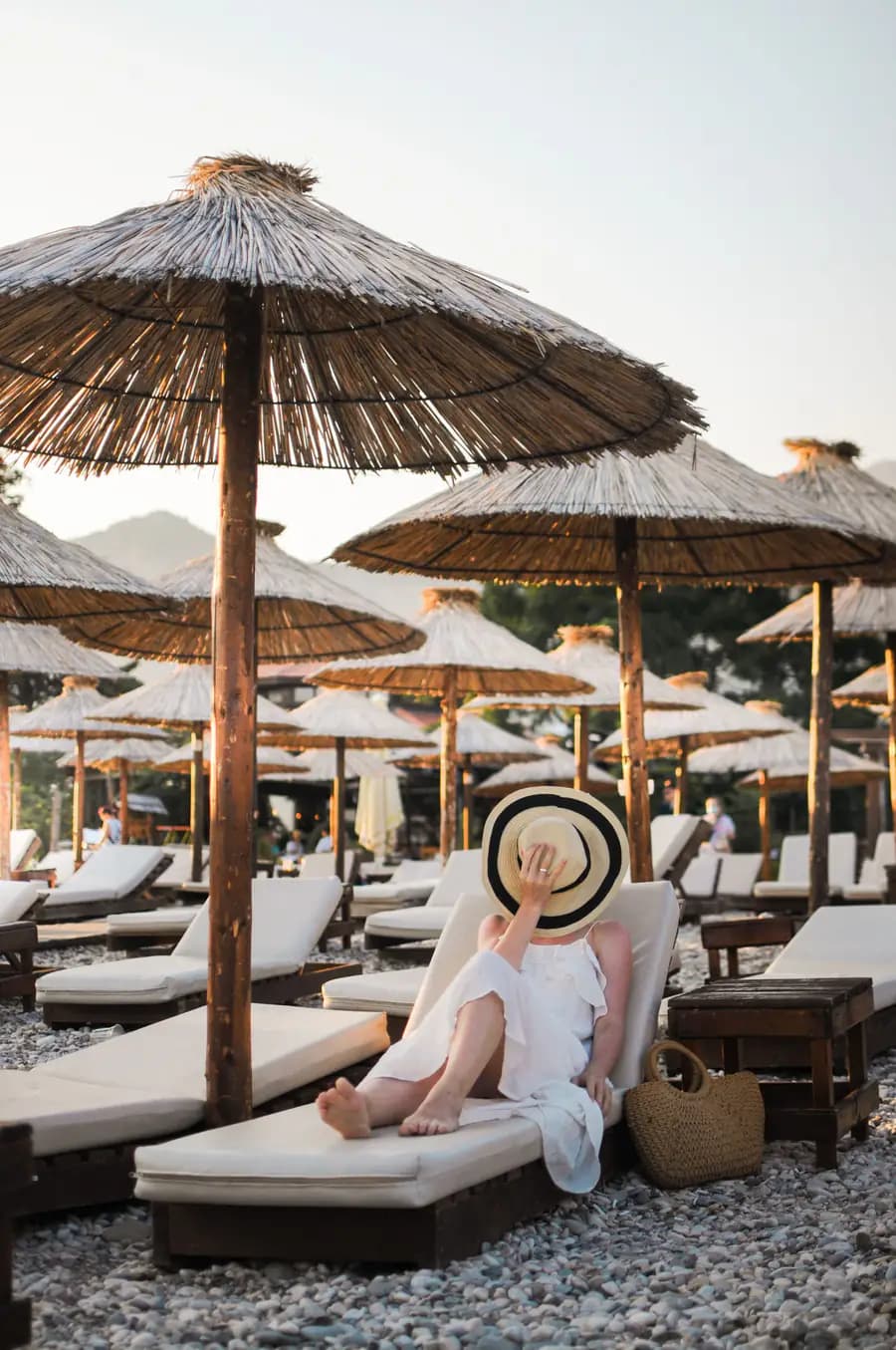 A lounger under a straw parasol by the sea, at the end of the day